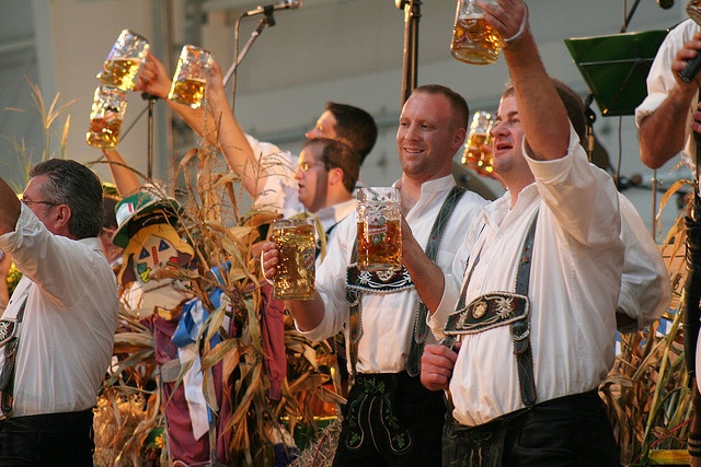 Group of men raising beer steins in the air at Oktoberfest celebration