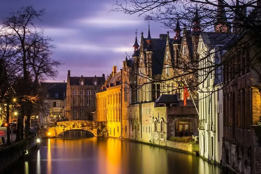 Bruges riverside buildings glowing with lights reflected in the water at night